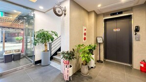 A hotel lobby with a reception desk, a clock, potted plants, an elevator, and a fire extinguisher. - ANYANG IT CENTRO HOTEL (Anyang)