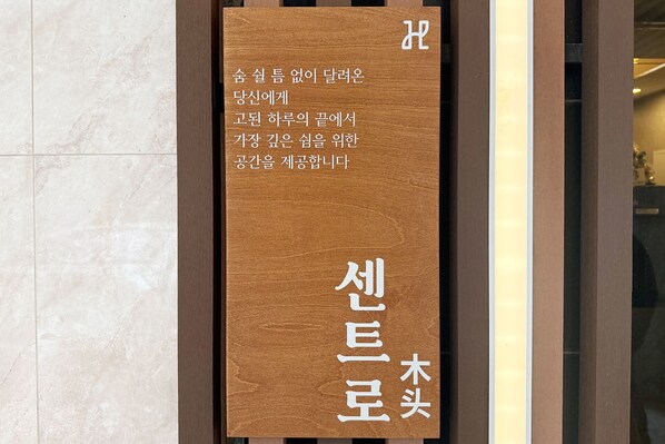 Ein Holzschild mit koreanischer Schrift, vermutlich zur Kennzeichnung eines Hotels oder einer Unterkunft.