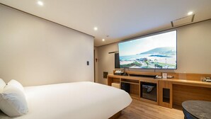 A hotel room with a bed, a TV mounted on the wall, a wooden desk, and a small table. - ANYANG IT CENTRO HOTEL (Anyang)