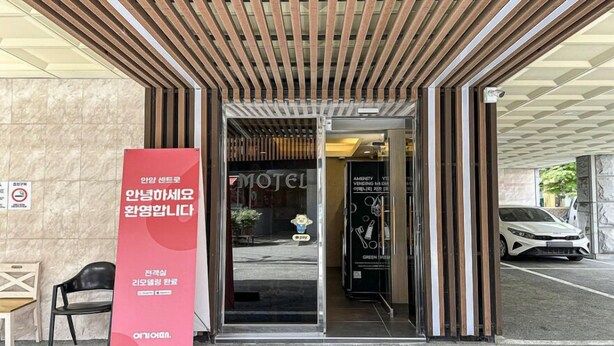 A hotel entrance with a modern design, including a wooden slatted roof and a large red sign advertising a green initiative. - ANYANG IT CENTRO HOTEL (Anyang)