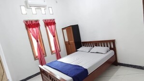 Un dormitorio con cama de madera, ropa de cama blanca y cortinas rojas.