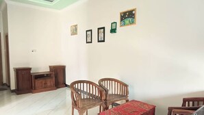 Un comedor con mesa y sillas de madera, mantel rojo y un mueble.