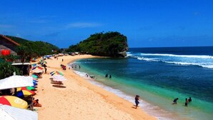 Una playa con agua turquesa cristalina, una orilla de arena y una pequeña isla con vegetación.