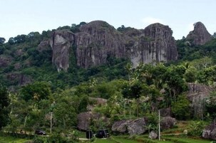 Paisagem montanhosa com formações rochosas imponentes e vegetação exuberante.