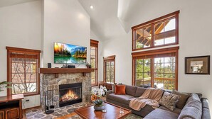 A living room with a stone fireplace, a large flat-screen TV, a sofa, and a coffee table.