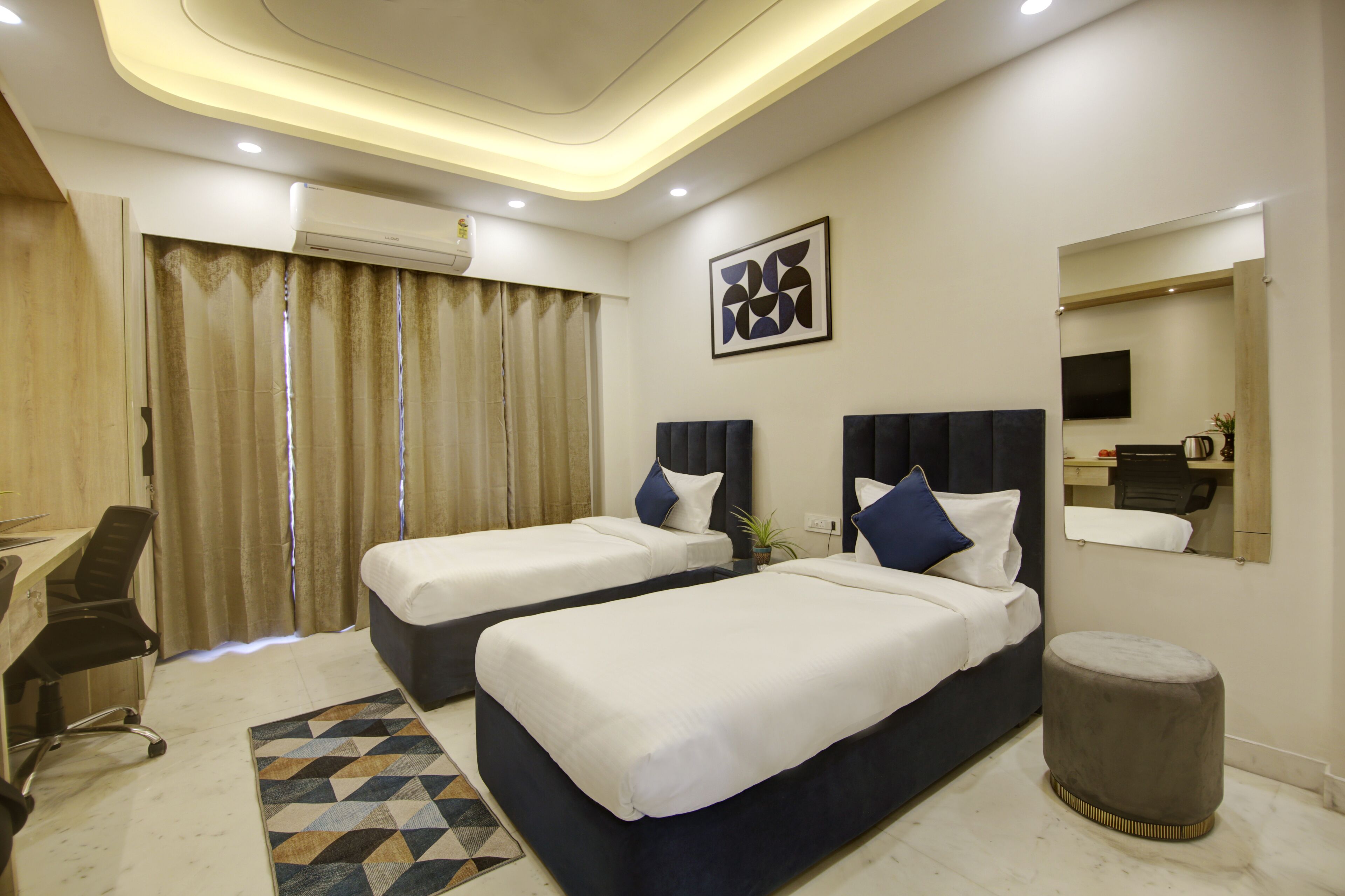 A hotel room with two beds, a desk, and a chair.
