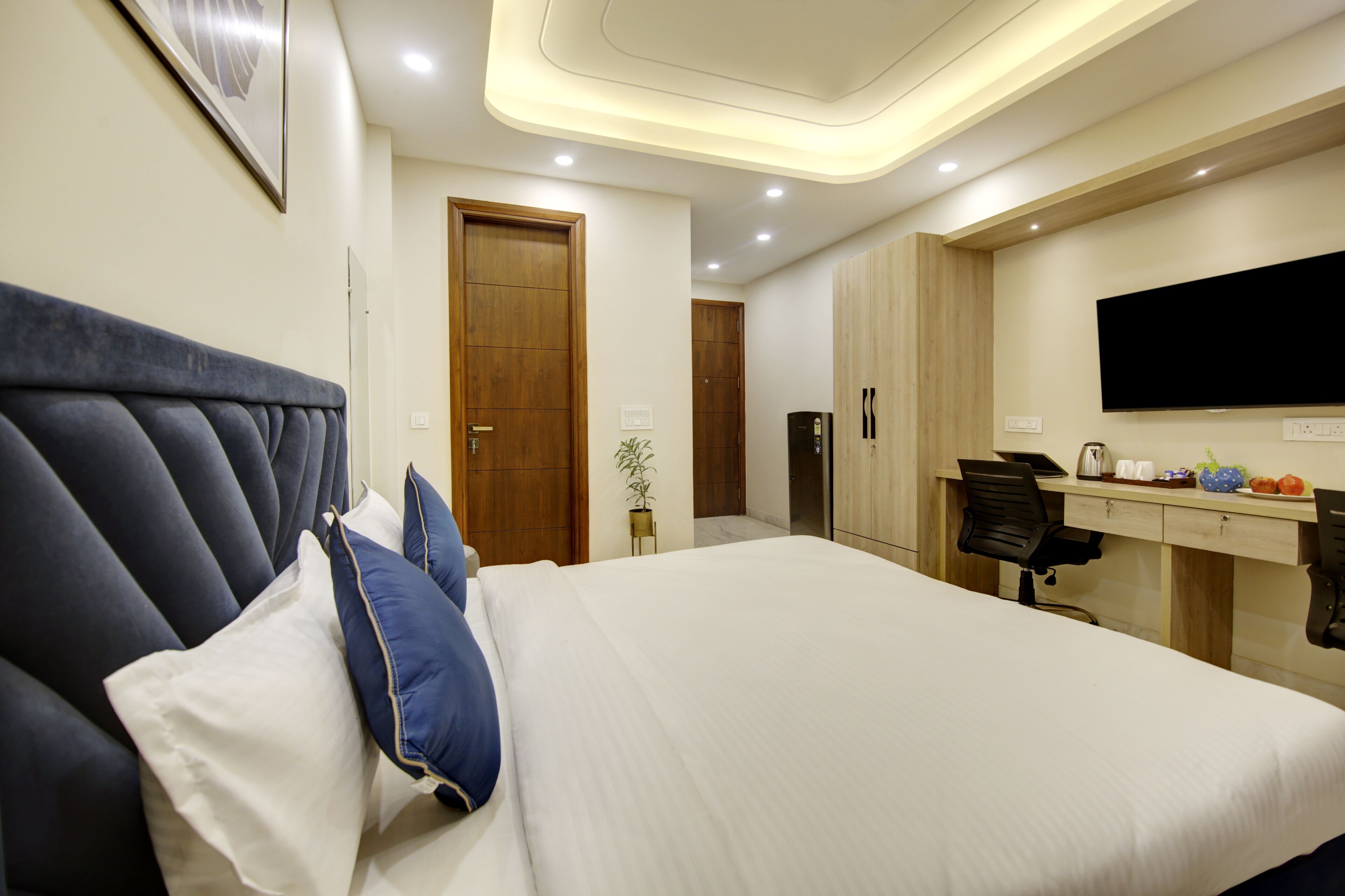 A modern hotel room with a large bed, a desk, and a television.