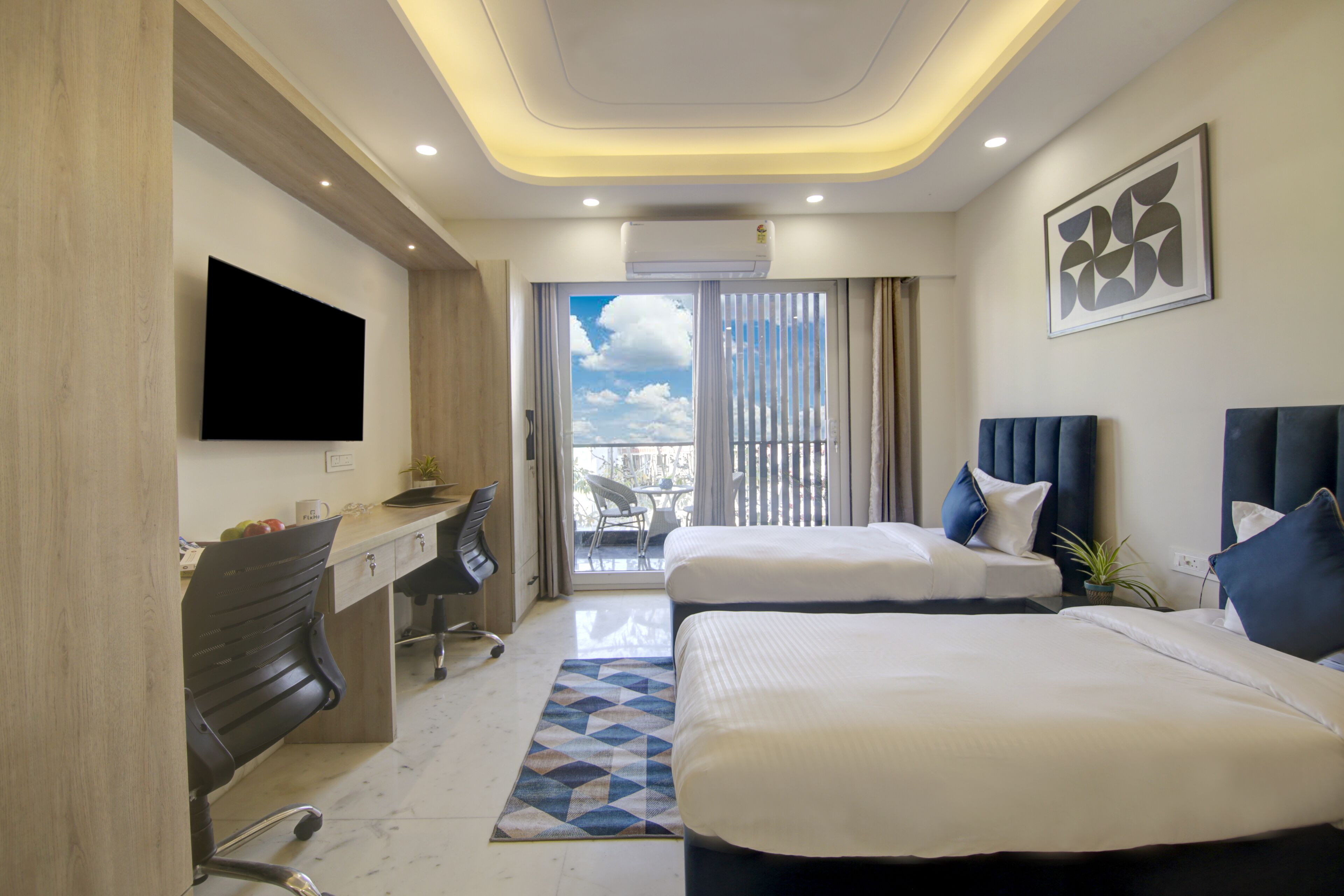 A hotel room with two beds, a desk, a TV, and a balcony with a view.
