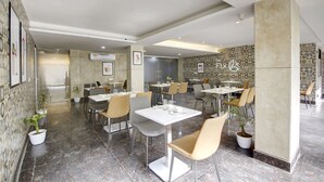 Un restaurante moderno con suelo de mármol, varias mesas y sillas, y plantas en macetas.