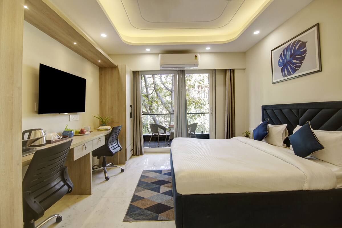 Ein Hotelzimmer mit Bett, Schreibtisch, Stuhl, Fernseher und einem Balkon mit Blick.