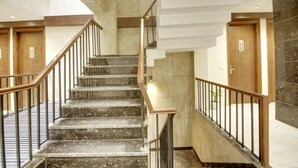 Una escalera moderna con peldaños de mármol y barandillas metálicas que conduce a una puerta de madera.