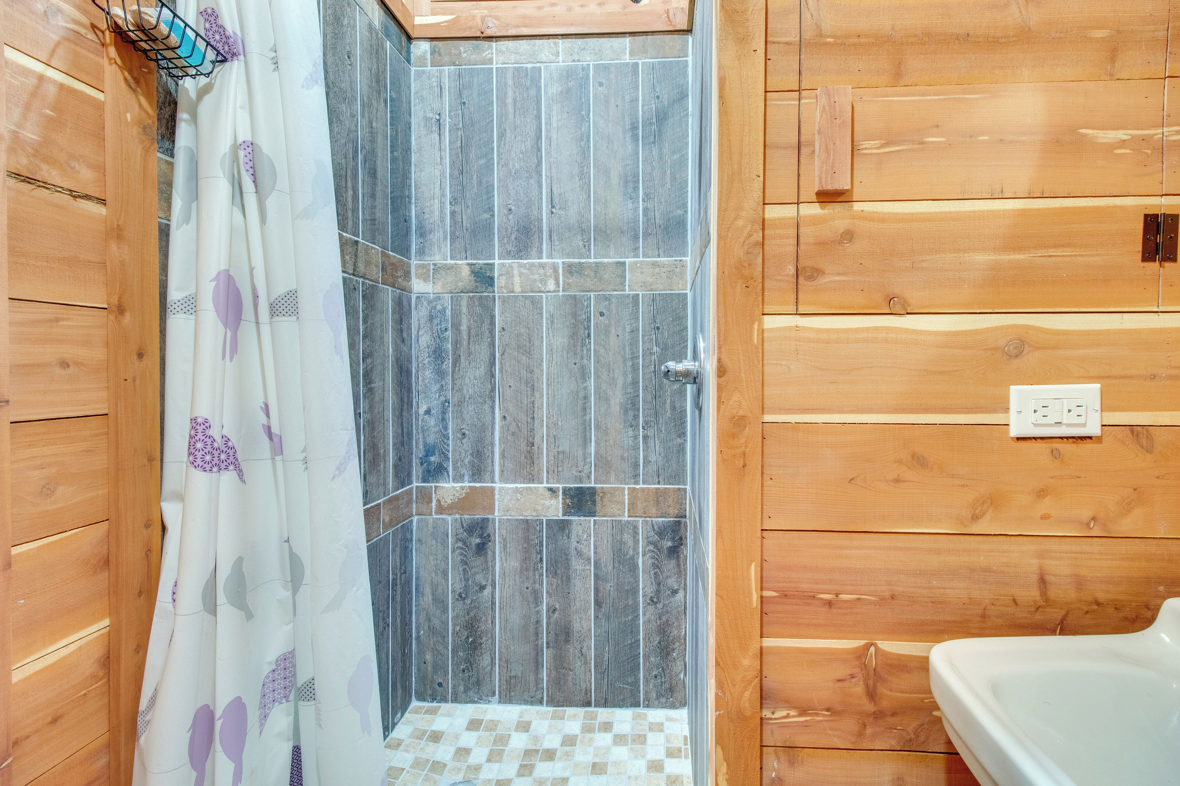 A wooden-paneled bathroom with a shower area and a toilet.