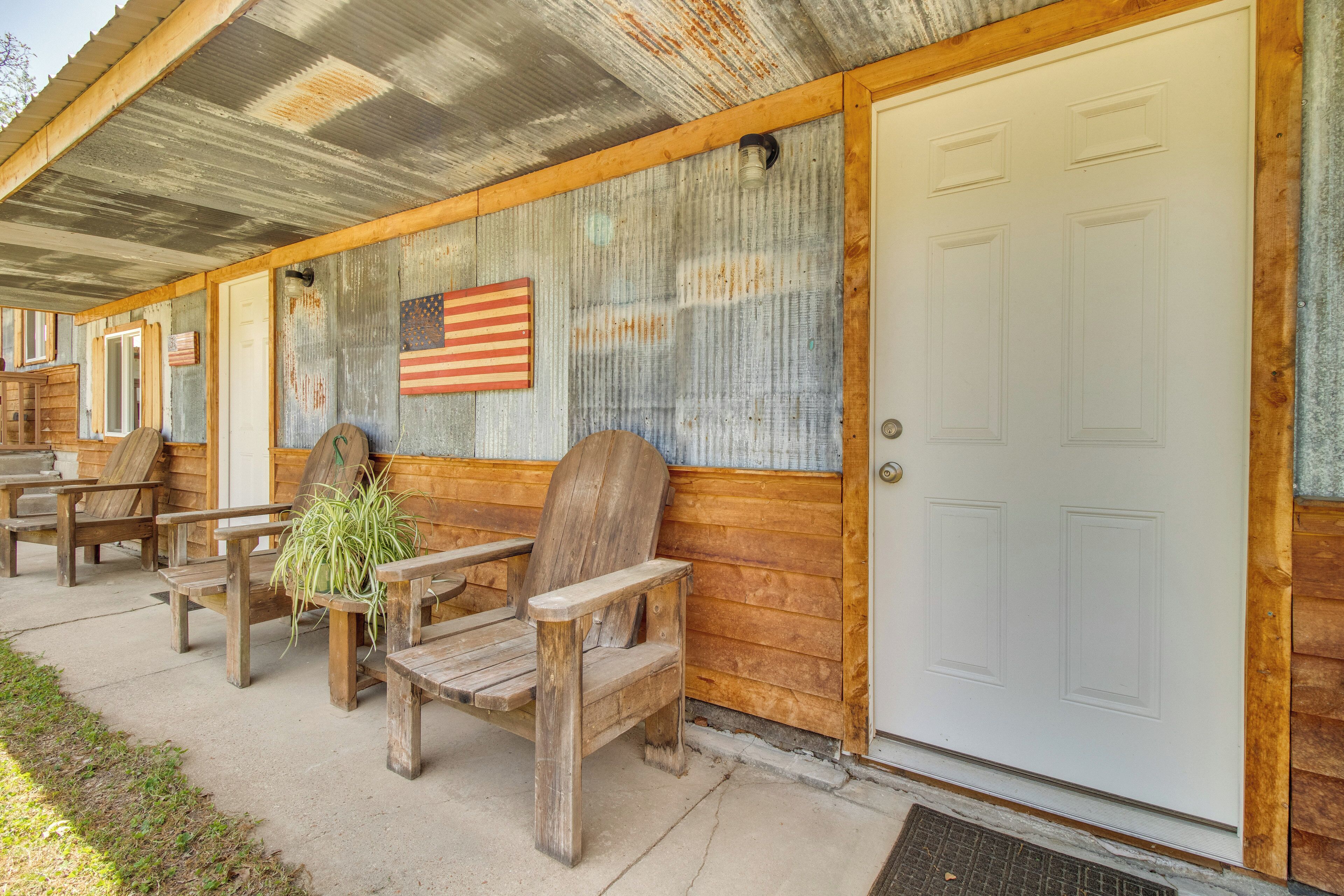 A covered porch with wooden benches and a potted plant.