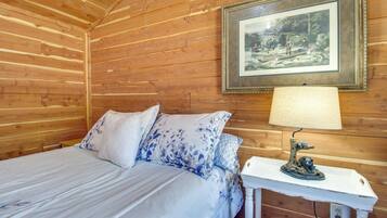 Una camera in legno con un letto, un quadro appeso alla parete e una lampada da tavolo.