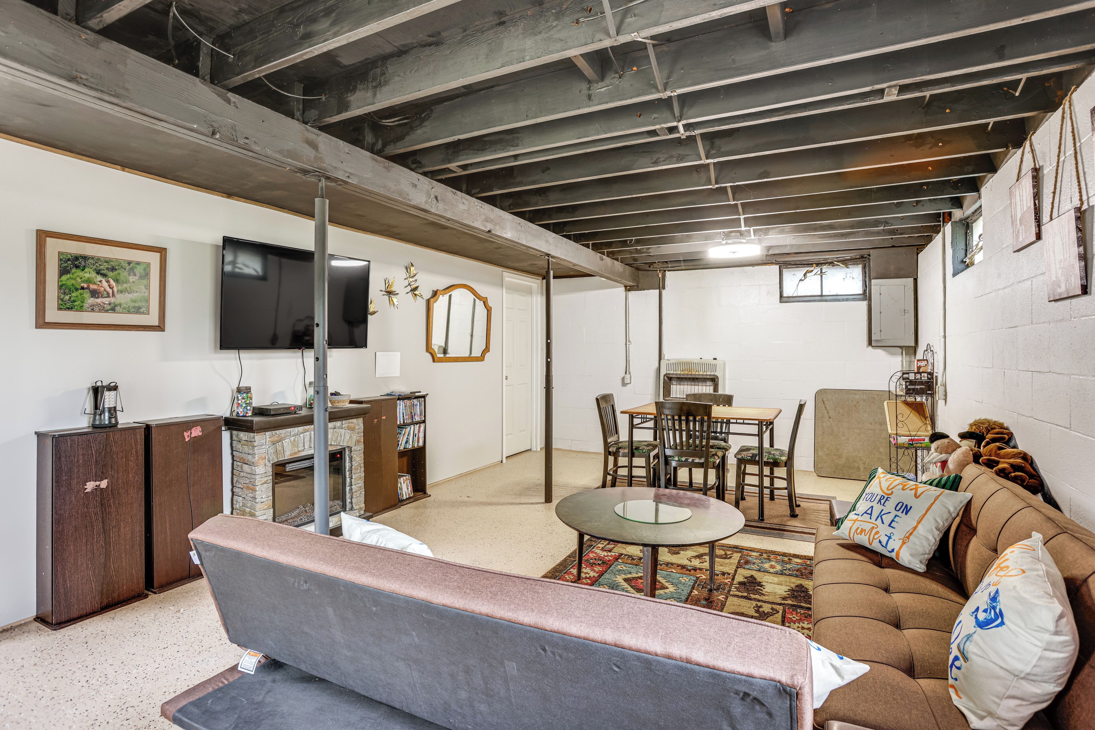 A room with a sofa, a dining table, and a TV mounted on the wall.
