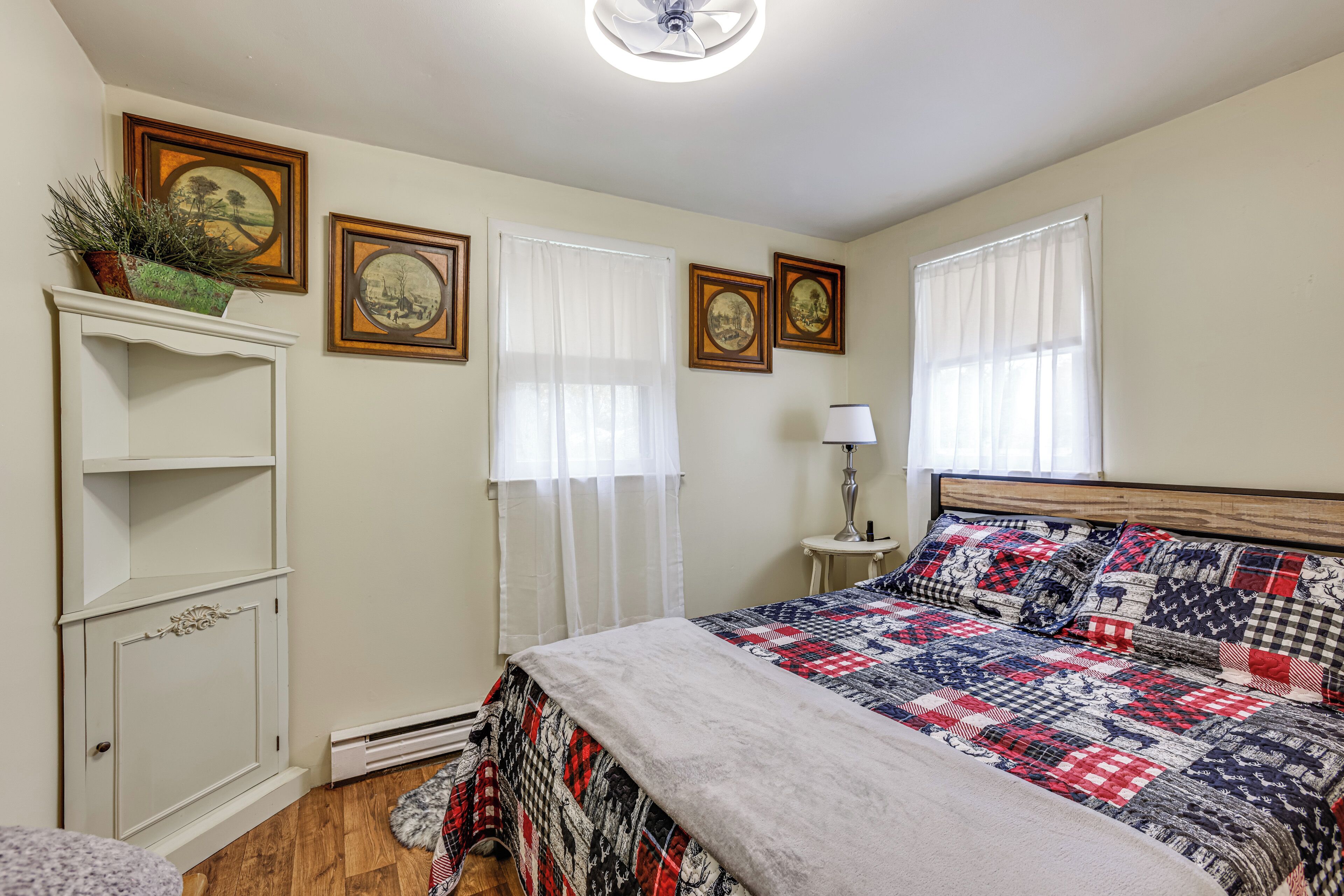 A bedroom with a bed, a dresser, a radiator, and framed pictures on the wall.