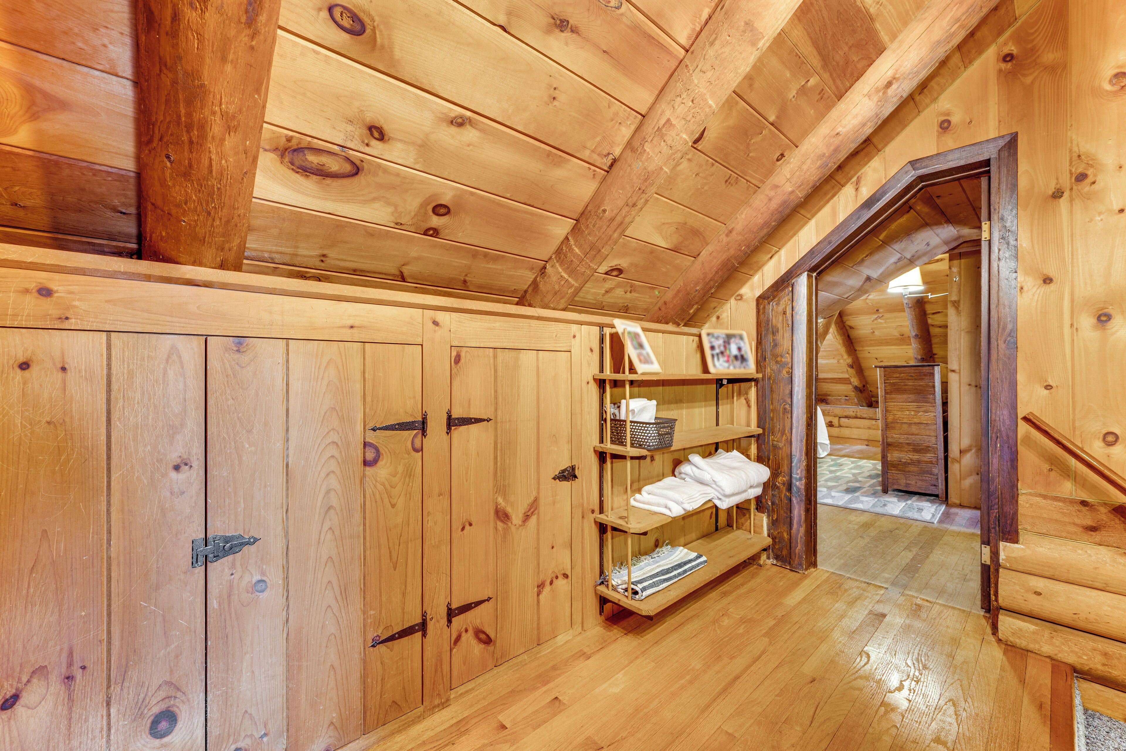 Un intérieur en bois avec un escalier en bois, une étagère avec des serviettes pliées et une porte donnant sur une autre pièce.