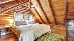 A wooden cabin bedroom with a bed, a ceiling fan, a window, and a nightstand. - 2 Mi to Lake Willoughby: Peaceful Log Cabin! (West Burke)