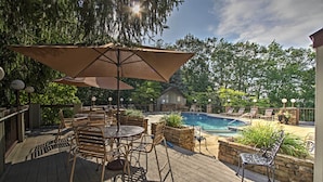 A wooden deck with outdoor furniture, a swimming pool, and a stone wall. - 3 Mi to Gsmnp! Family Condo w/ Pool & Views (Gatlinburg)