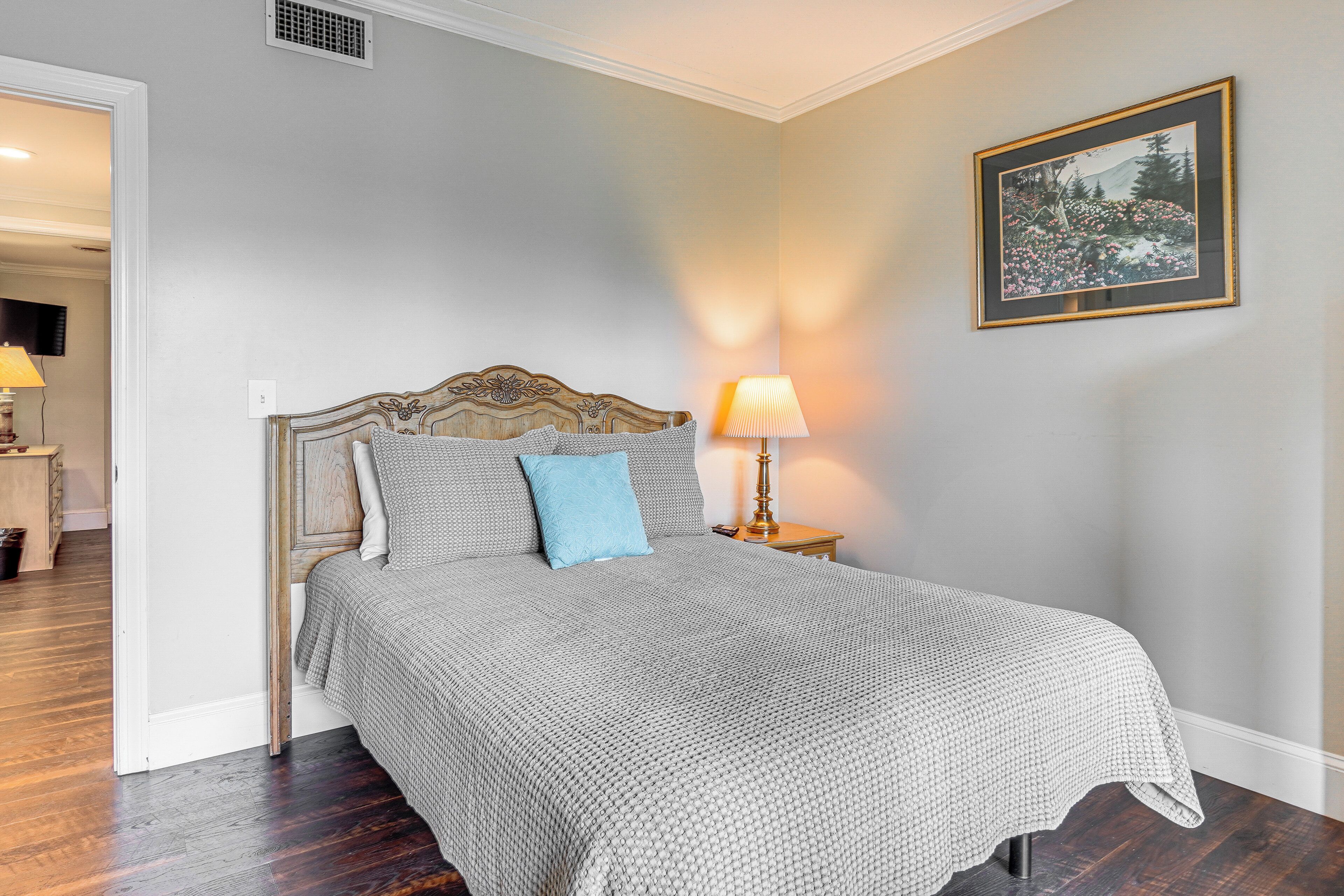 A neatly made bed with a patterned bedspread, a blue pillow, and a wooden headboard.