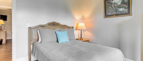 A neatly made bed with a patterned bedspread, a blue pillow, and a wooden headboard.