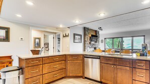 A modern kitchen with wooden cabinets, a dishwasher, and a stone backsplash. - 3 Mi to Gsmnp! Family Condo w/ Pool & Views (Gatlinburg)