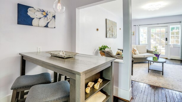 Un coin repas avec une table en bois, deux chaises grises à revêtement rembourré et un luminaire suspendu.