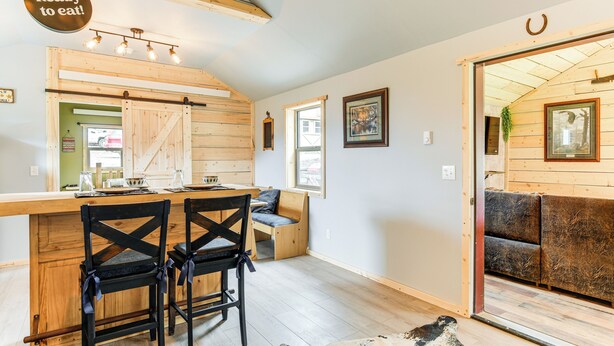 A cozy interior with a wooden bar, two black chairs, a sofa, and a cowhide rug. - Fishing & Views: 'river Paradise' in Dubois! (Dubois)