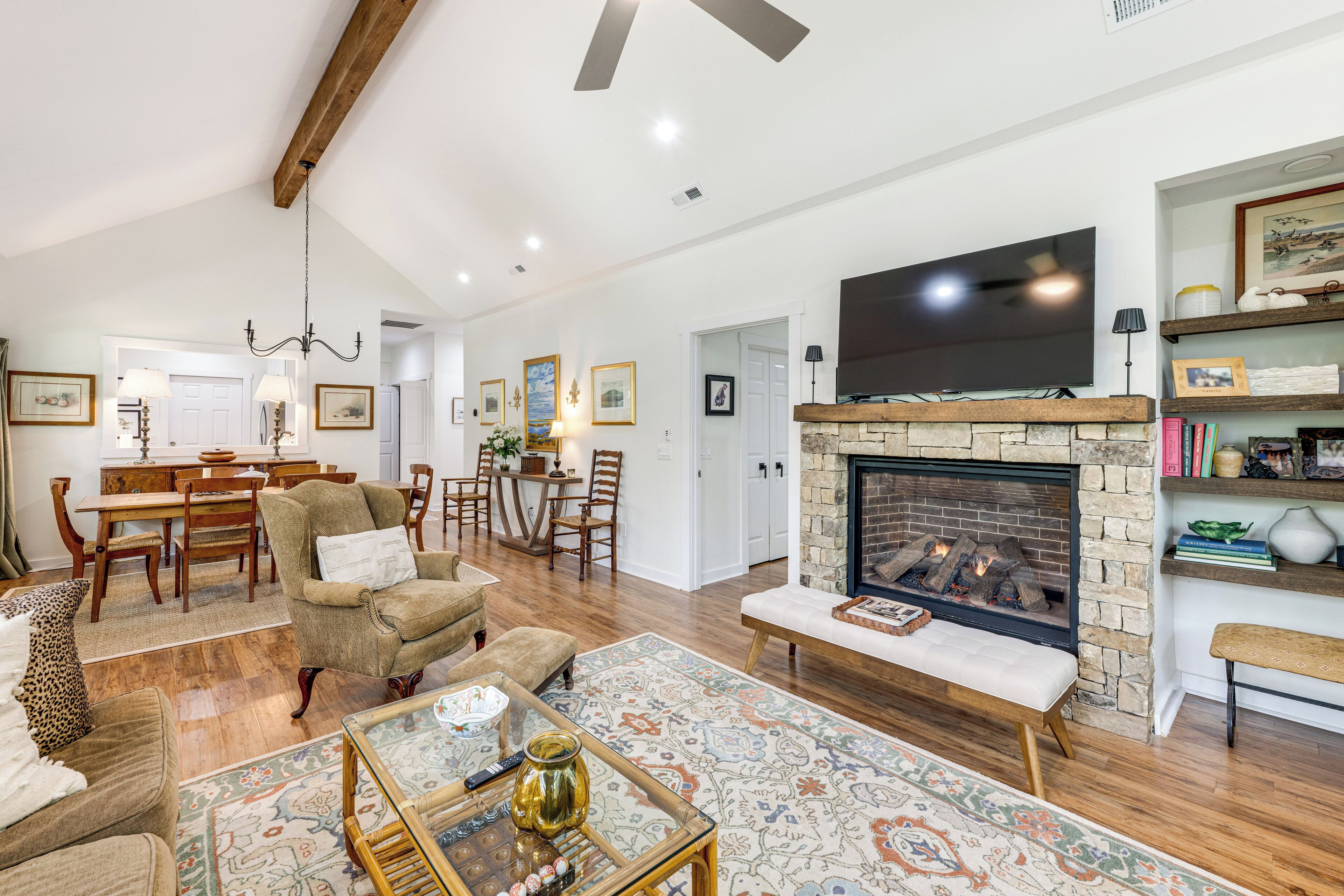 Un salón amplio con chimenea, zona de comedor y televisor sobre la chimenea.