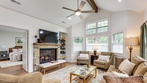 A spacious living room with a fireplace, comfortable seating, and large windows.