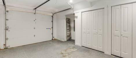 A garage with concrete floor, white garage doors, and a ceiling fan.