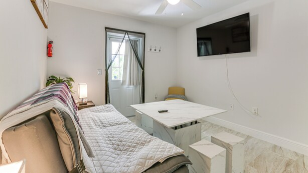 Une chambre à coucher comprenant un lit, un bureau, une chaise, un téléviseur et un ventilateur de plafond.
