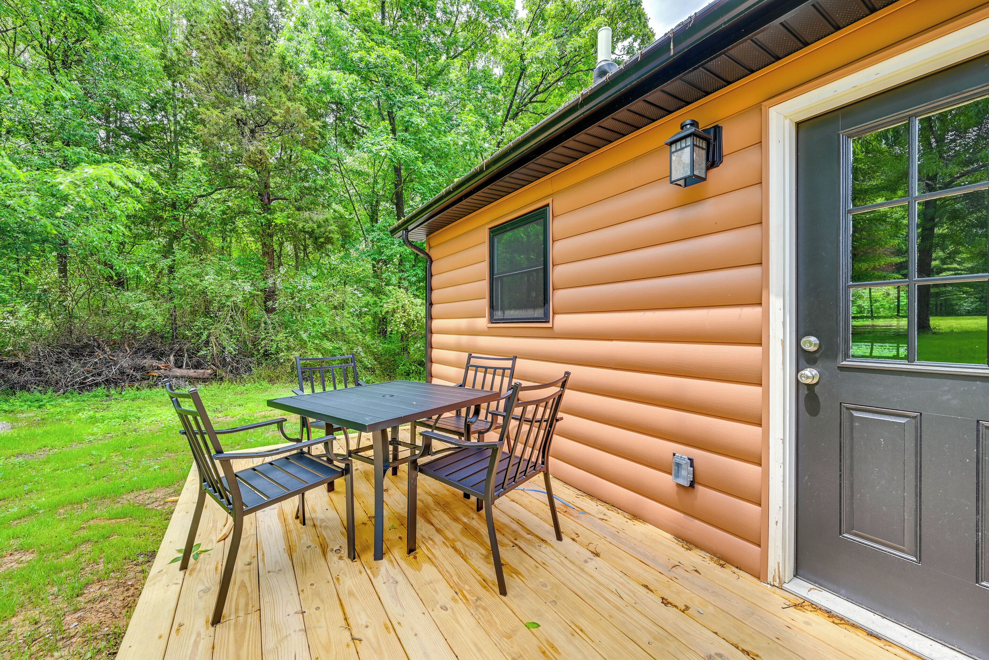 Une terrasse en bois avec une table et des chaises, une porte et une fenêtre.