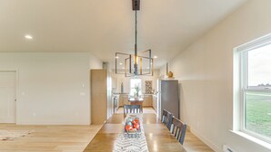 A spacious dining area with a long wooden table, a woven runner, and a modern pendant light. - Home 21 Mi to Glacier Nat'l Park: Boat, Fish, Hike (Columbia Falls)