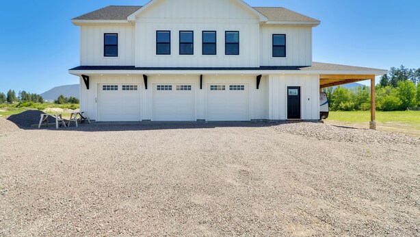 A two-story house with a covered driveway and a gravel front yard. - Home 21 Mi to Glacier Nat'l Park: Boat, Fish, Hike (Columbia Falls)