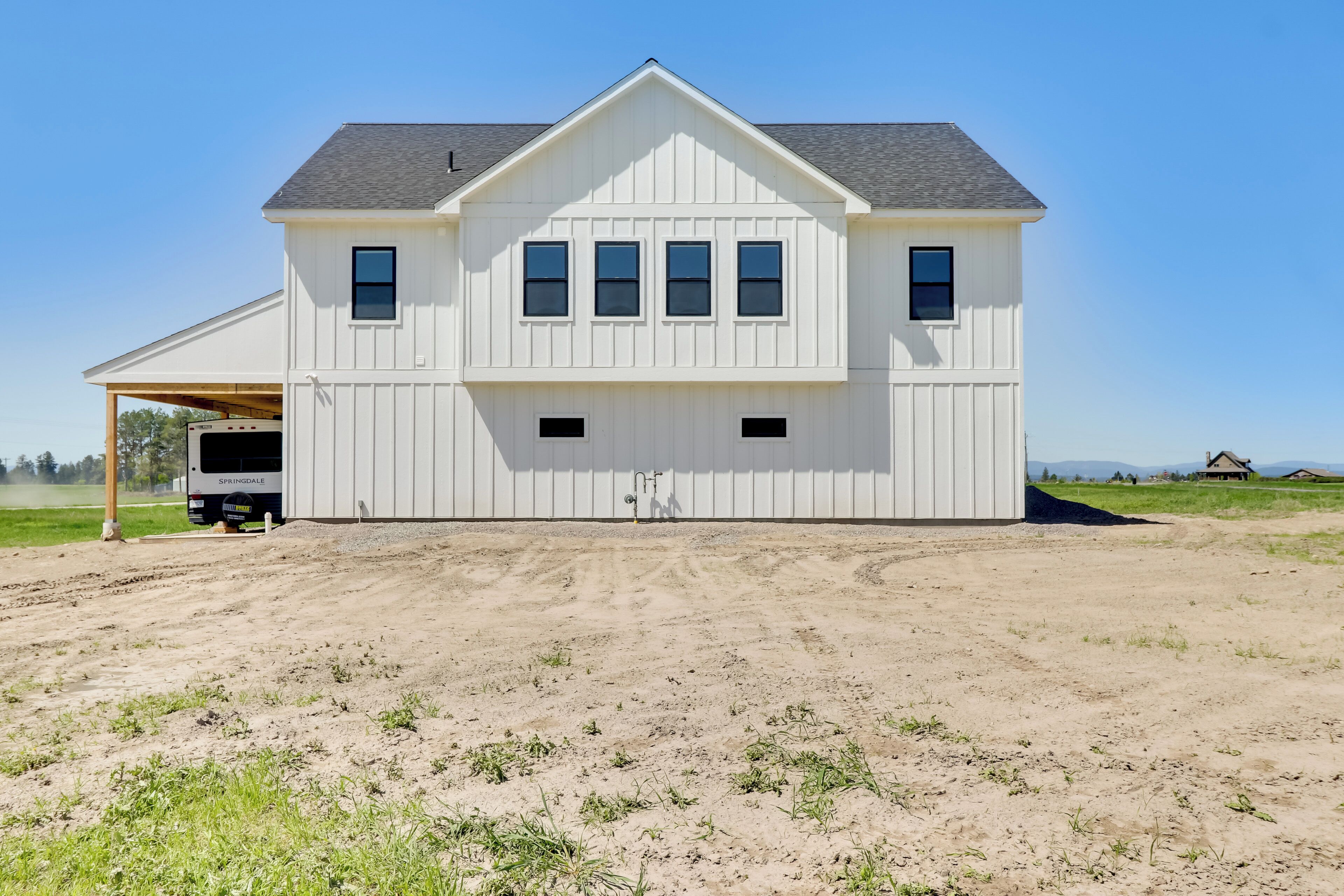 Ein großes, weißes, zweistöckiges Haus mit Garage, überdachter Auffahrt und Kieshof.