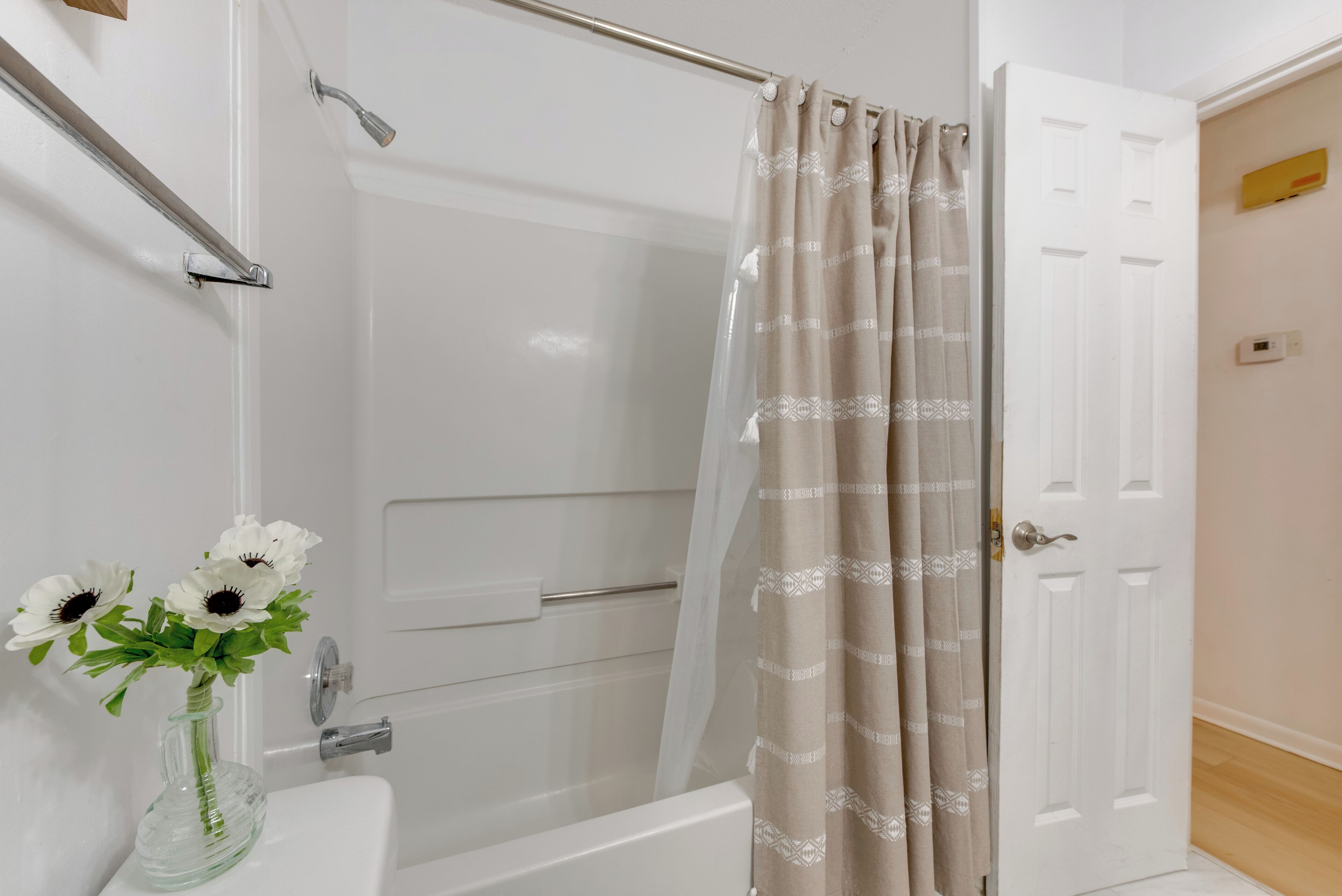A bathroom with a shower, a toilet, and a sink. There is a shower curtain and a door visible.