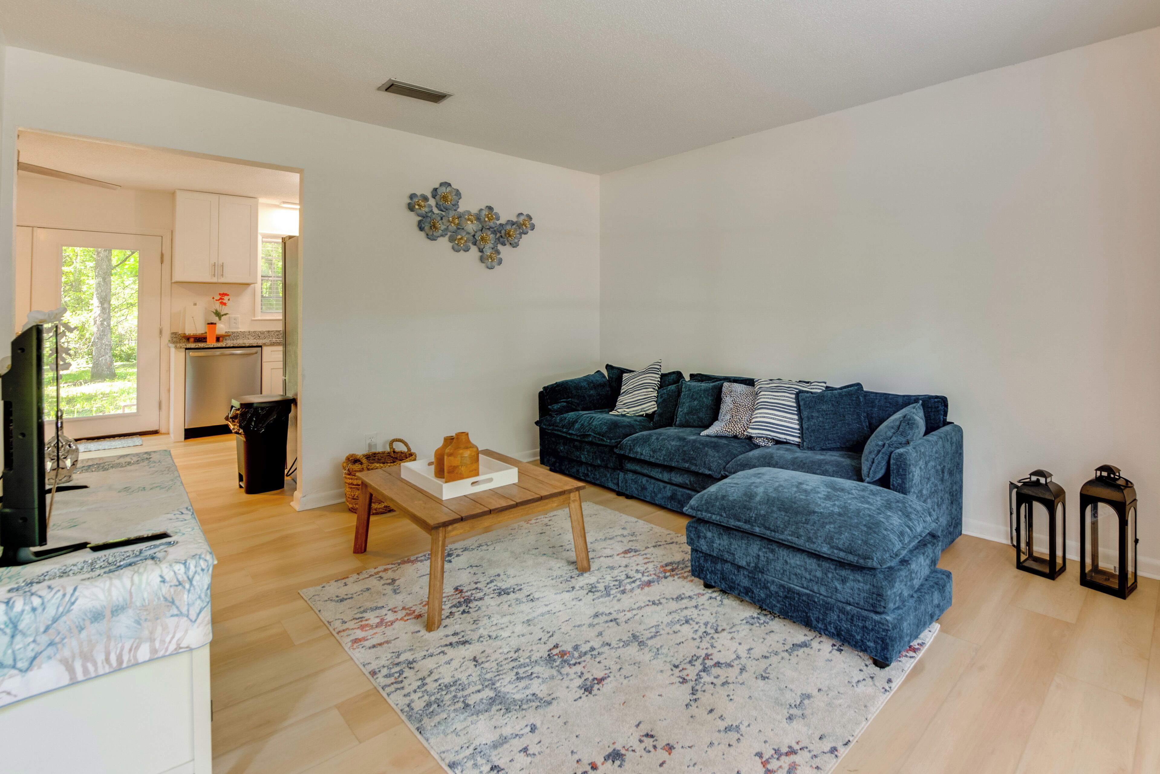 A living room with a blue sofa, a wooden coffee table, and a patterned rug.