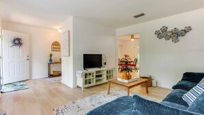 Un salon comprenant un canapé, une table basse, un téléviseur et un coin repas avec des chaises et une table.