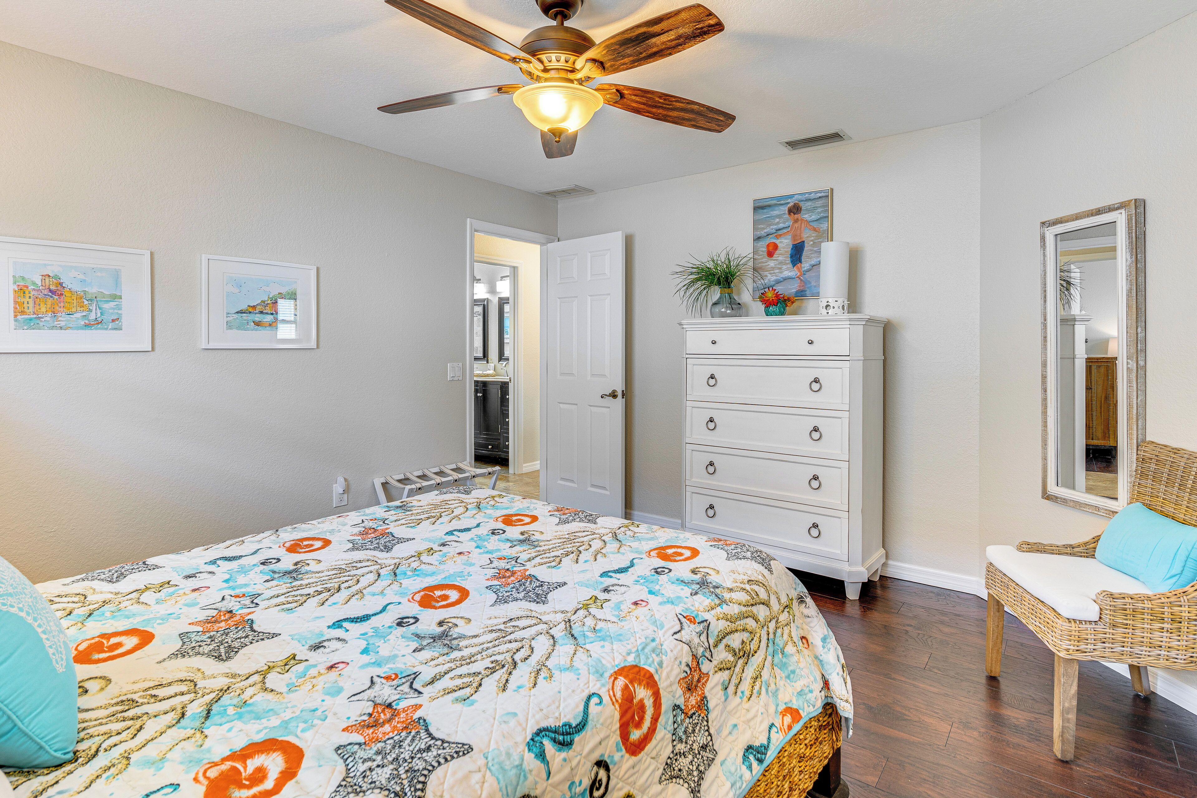 A bedroom with a bed, a dresser, a chair, and a ceiling fan.
