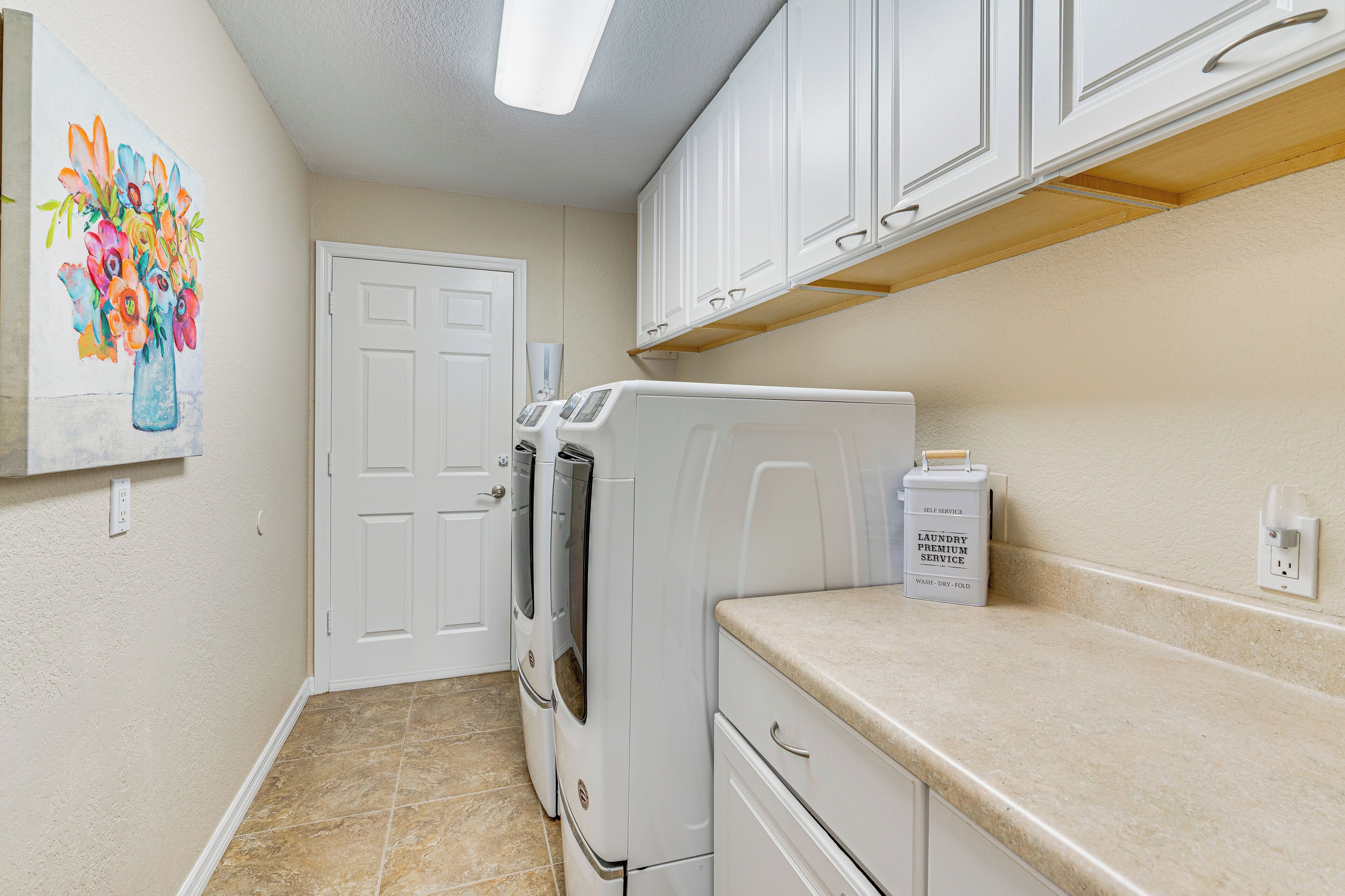 A laundry room with a washing machine, dryer, and a cabinet above the counter.