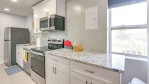 A modern kitchen with white cabinets, stainless steel appliances, and a granite countertop.