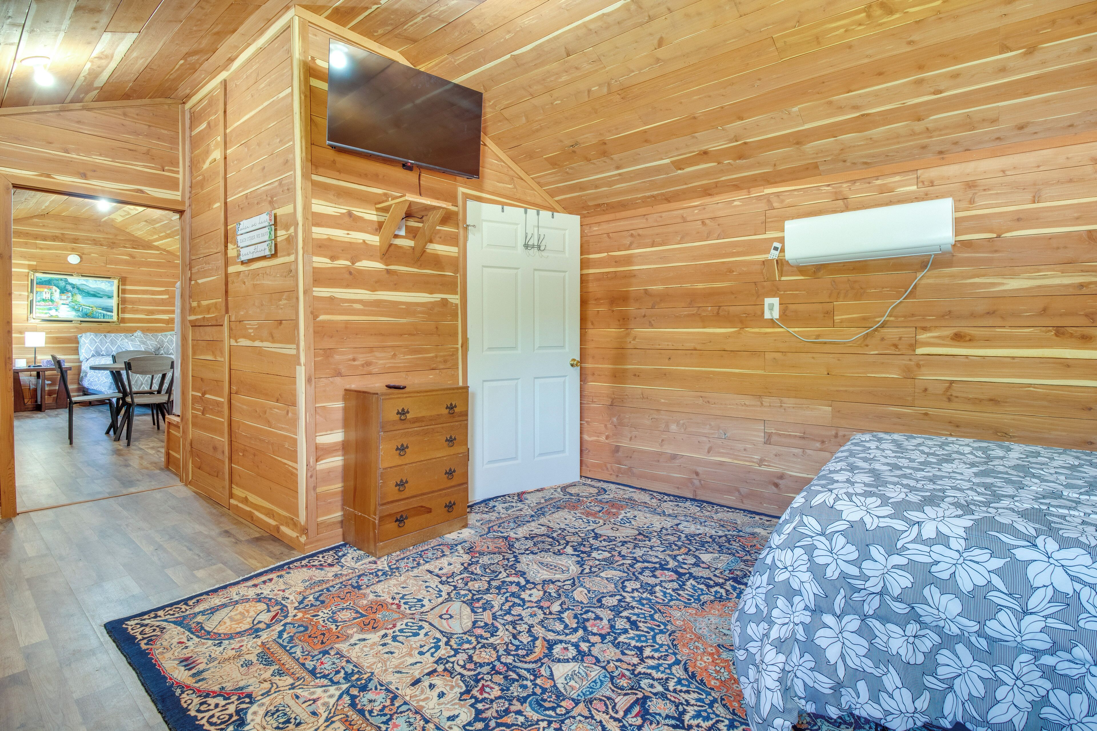 Een kamer met houten lambrisering, een bed, een dressoir, een deur en een wandairconditioner.