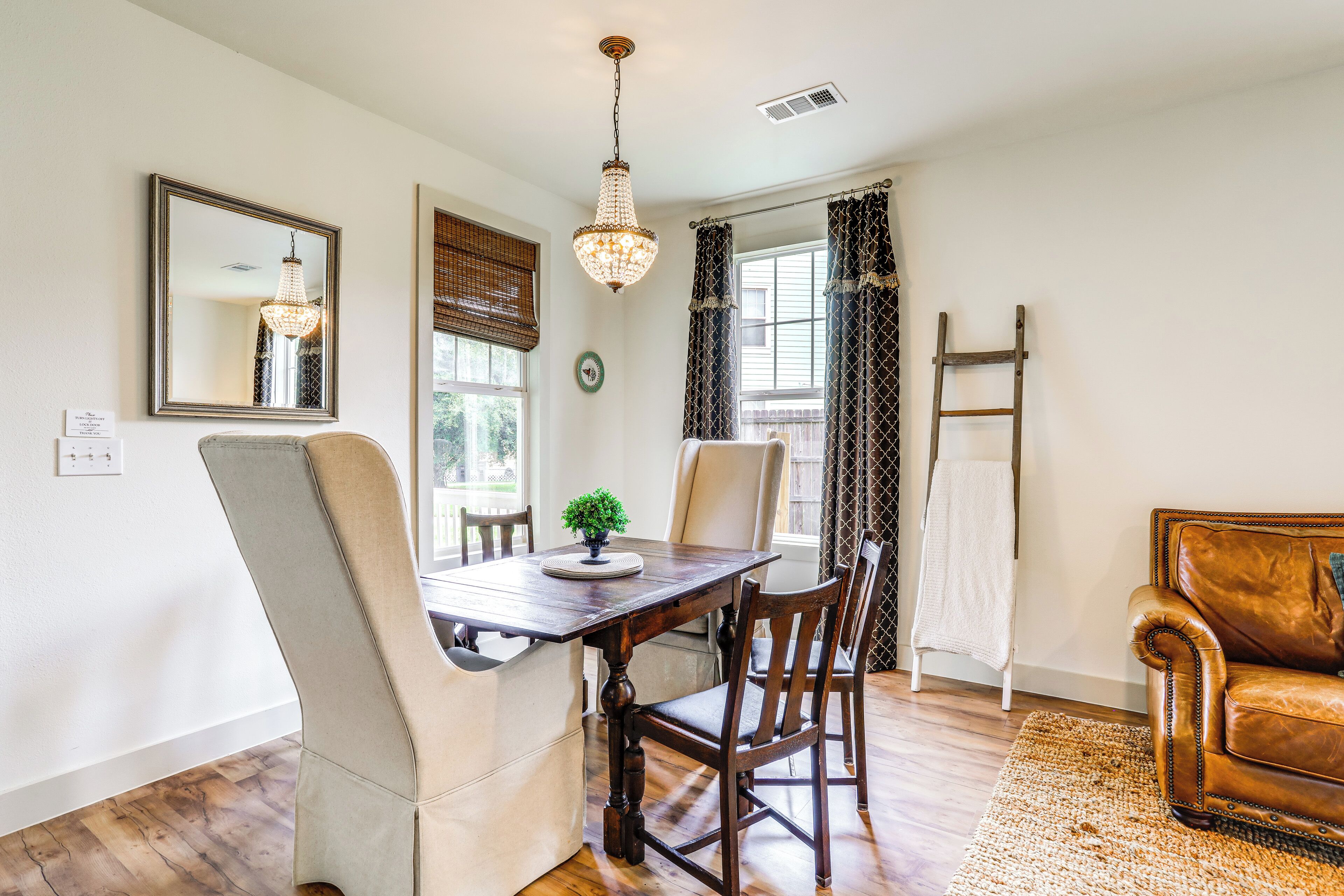 A dining area with a wooden table, chairs, a chandelier, and a leather sofa.