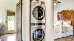 A laundry room with two front-loading washers and dryers, a wooden bed with a headboard, and a door leading to a balcony. - 2 Mi to L'auberge Casino: Home w/ Large Yard! (Baton Rouge)