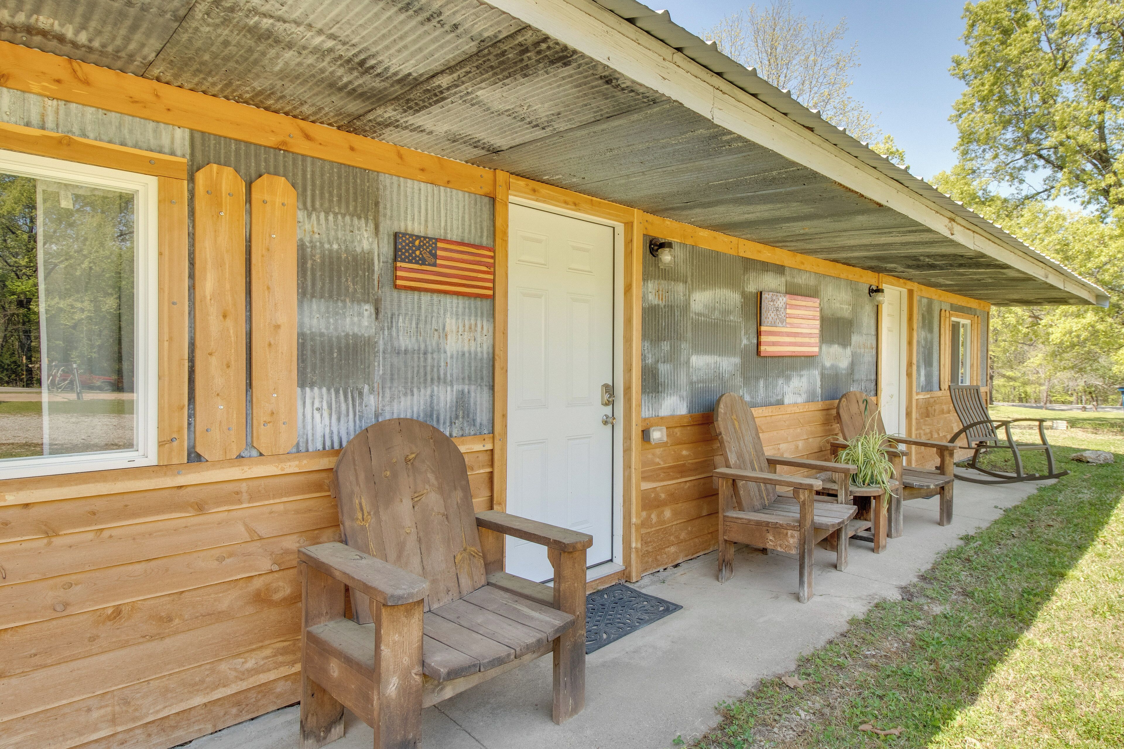 A wooden cabin with a porch, a door, and two windows.