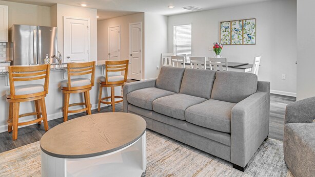 A modern living room with a grey sofa, wooden chairs, a round coffee table, and a dining area with a white table and chairs. - 3 Mi to Shore: Family Townhome in Surfside Beach (Surfside Beach)