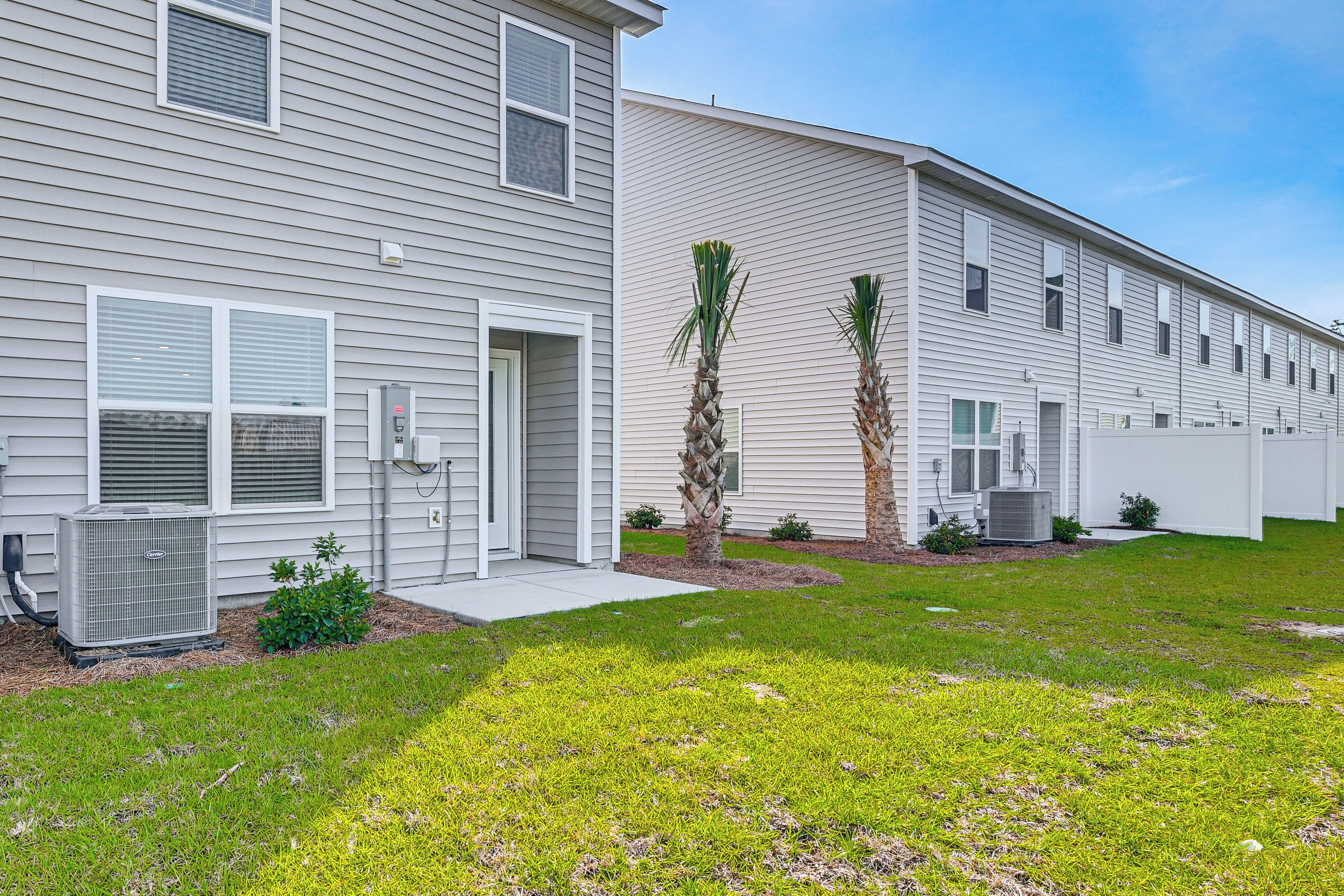 A two-story residential building with a front yard, a small garden, and two palm trees.