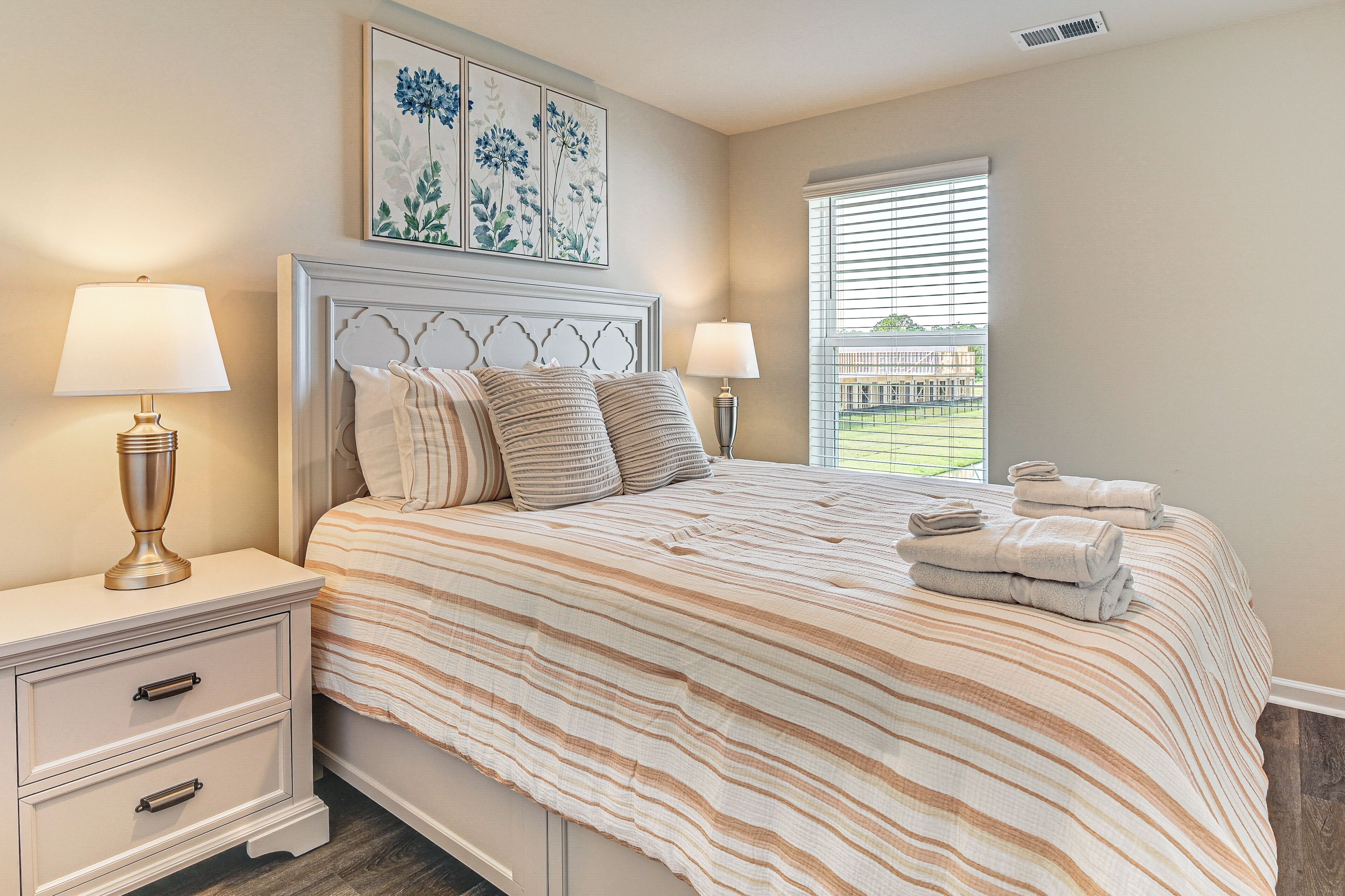 A bedroom with a bed, two bedside tables, and a window with blinds.