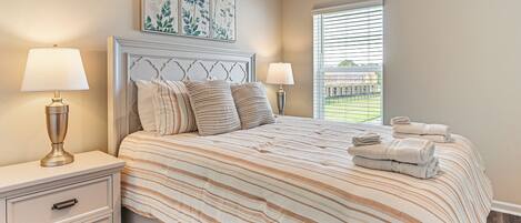 A bedroom with a bed, two bedside tables, and a window with blinds.